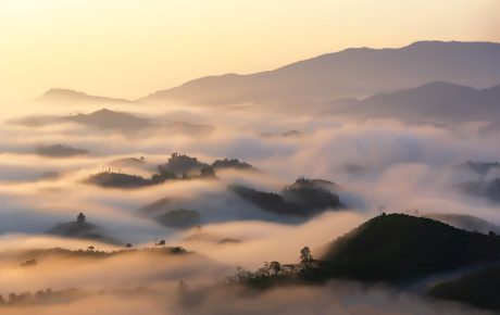 探险题材示意画面，山间古道与雾气，远处隐约有人影行走